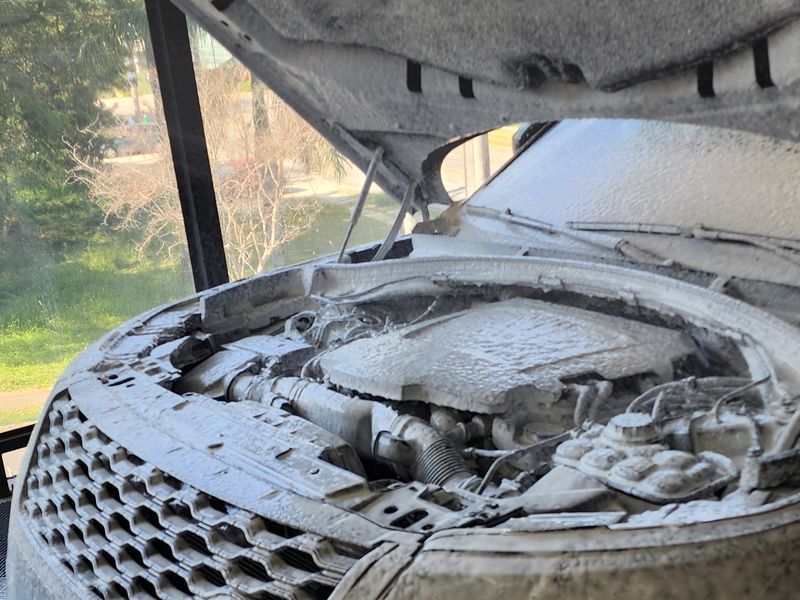 Cofre do motor de um SUV com espuma durante a lavagem de motor na Restauros